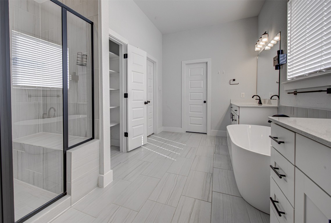 822 Wild Pecan Loop Buda, TX 78610 - Photo 25 of 33 Full bathroom featuring vanity, a stall shower, a freestanding bath, and a spacious closet