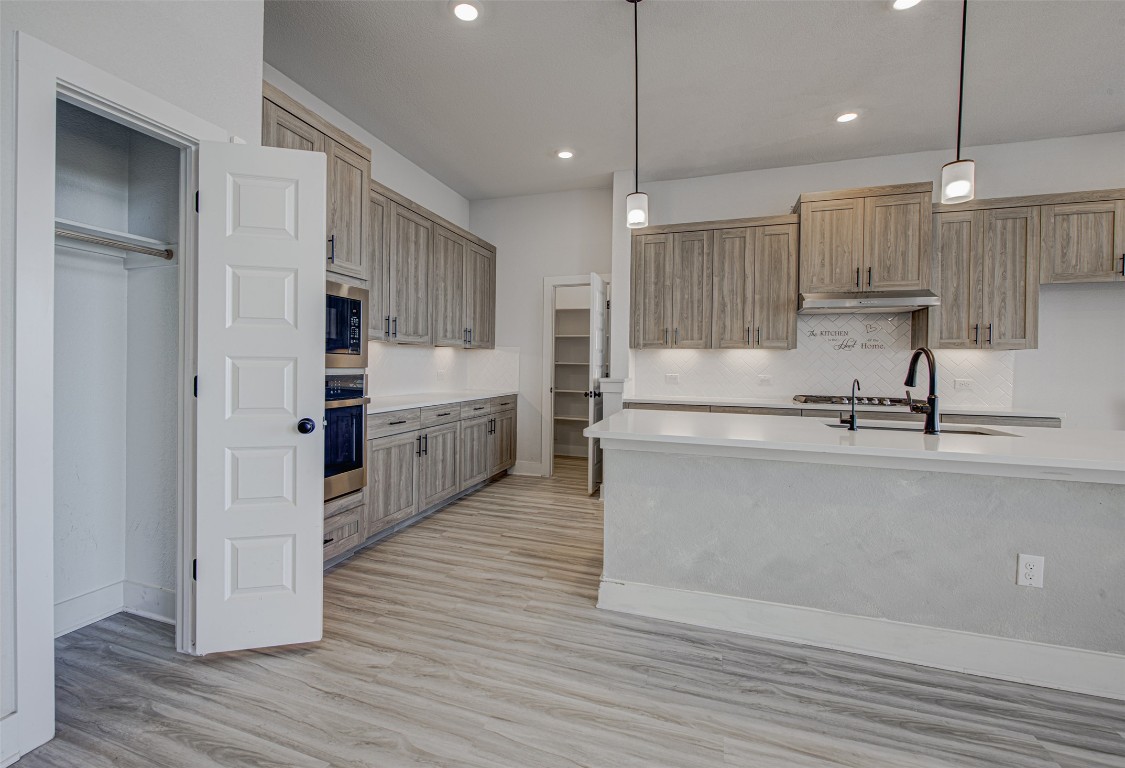 822 Wild Pecan Loop Buda, TX 78610 - Photo 4 of 33 Kitchen featuring pendant lighting, light wood finished floors, decorative backsplash, appliances with stainless steel finishes, and recessed lighting