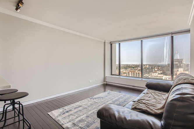5455 North Sheridan Road, Unit 3105 Chicago, IL 60640 - Photo 5 of 11 a bedroom with a bed and a couch with wooden floor