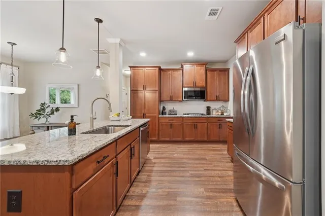 a kitchen with stainless steel appliances granite countertop a refrigerator a sink and a stove