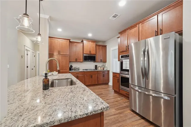 a kitchen with stainless steel appliances granite countertop a refrigerator a stove a sink and a wooden floors