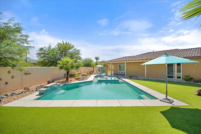 a view of a swimming pool with lawn chairs under an umbrella