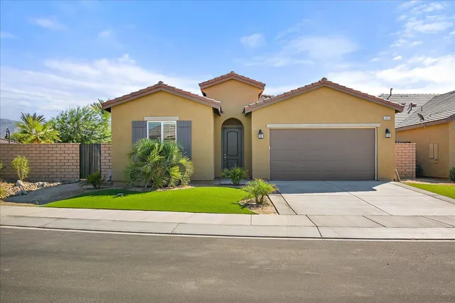 a front view of yellow house with a yard and garage