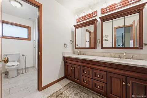 a spacious bathroom with a toilet a double vanity sink and a mirror