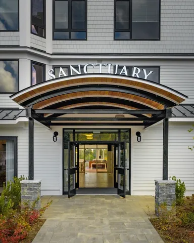a front view of a building with street view and trees
