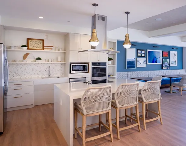 a dining hall with stainless steel appliances granite countertop a stove a kitchen island a dining table and chairs with wooden floor