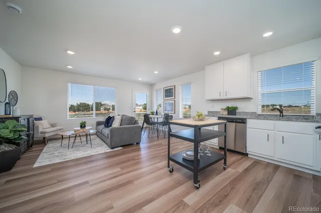 a living room with furniture a wooden floor and a kitchen view
