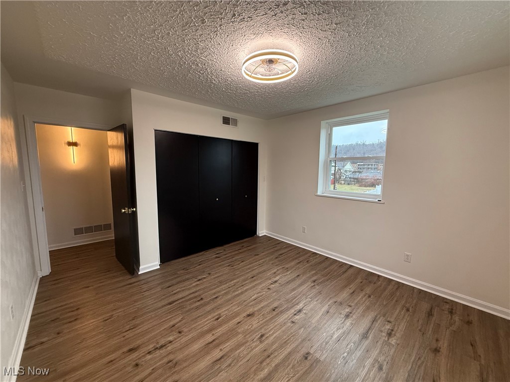 522 North 3rd Street Toronto, OH 43964 - Photo 36 of 47 Unfurnished bedroom featuring wood finished floors, a textured ceiling, and a closet