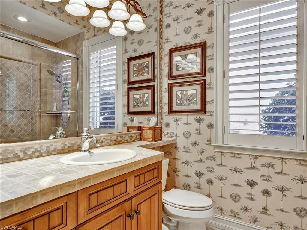 9113 Terrabella Court Naples, FL 34109 - Photo 35 of 47 a bathroom with a sink a toilet a mirror and a window