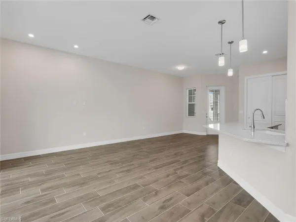 a large kitchen with stainless steel appliances granite countertop a stove a refrigerator a sink and white cabinets with wooden floor