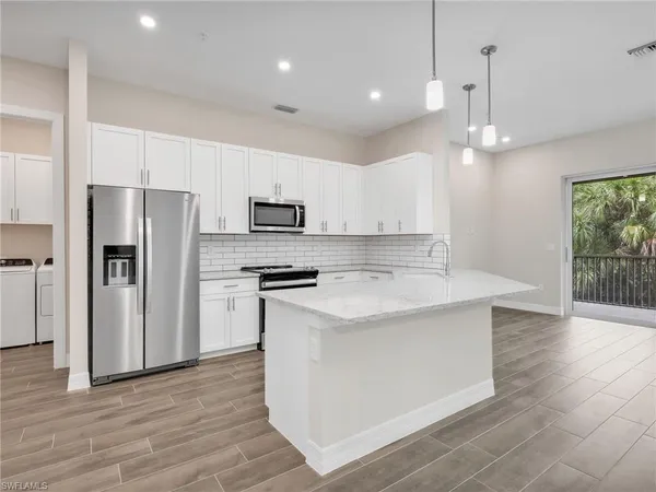 a view of kitchen with kitchen island white cabinets and refrigerator