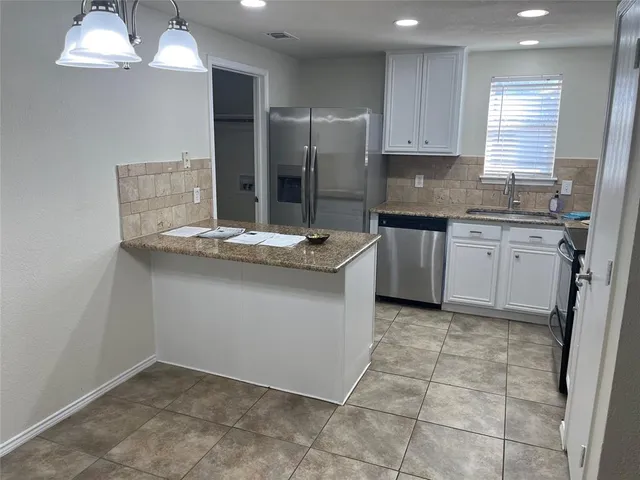 a kitchen with granite countertop a sink stove and refrigerator