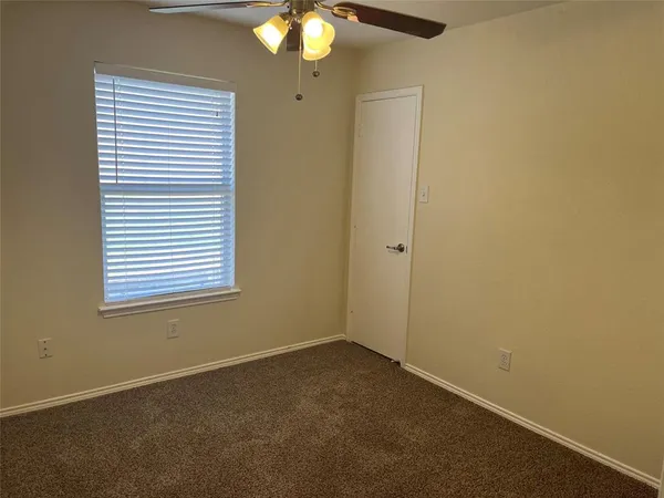 an empty room with a chandelier fan and windows