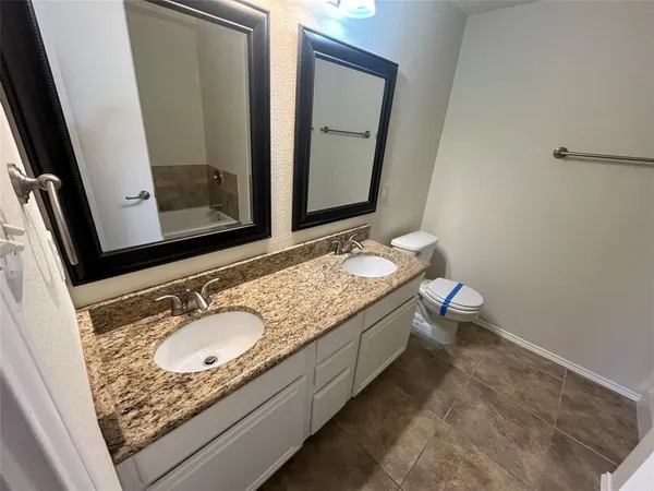 a bathroom with a granite countertop toilet sink and mirror