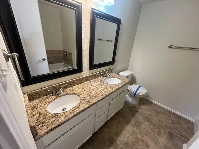 a bathroom with a granite countertop toilet sink and mirror