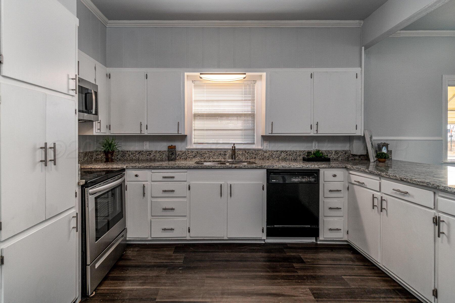 700 21st Street Canyon, TX 79015 - Photo 11 of 30 a kitchen with granite countertop a stove cabinets and wooden floor