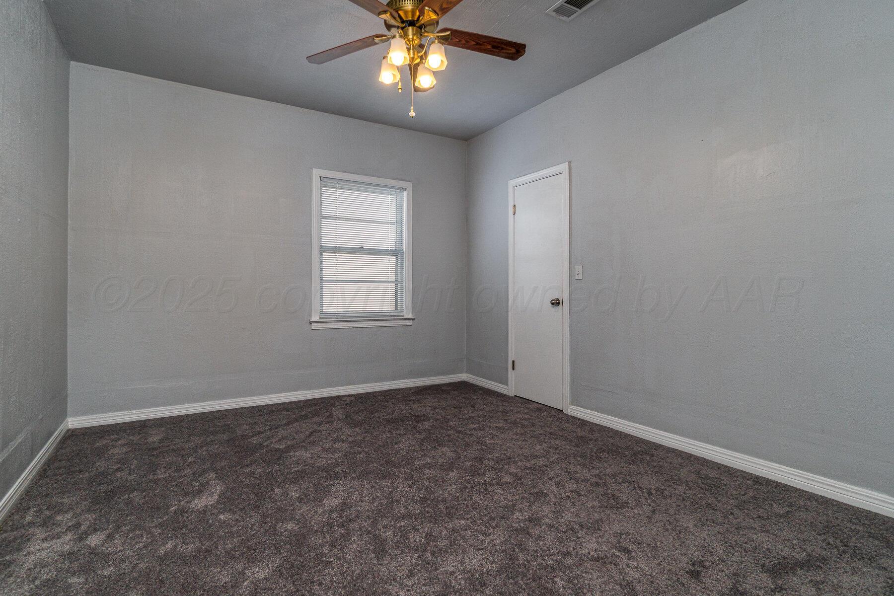 700 21st Street Canyon, TX 79015 - Photo 16 of 30 an empty room with a chandelier fan and windows