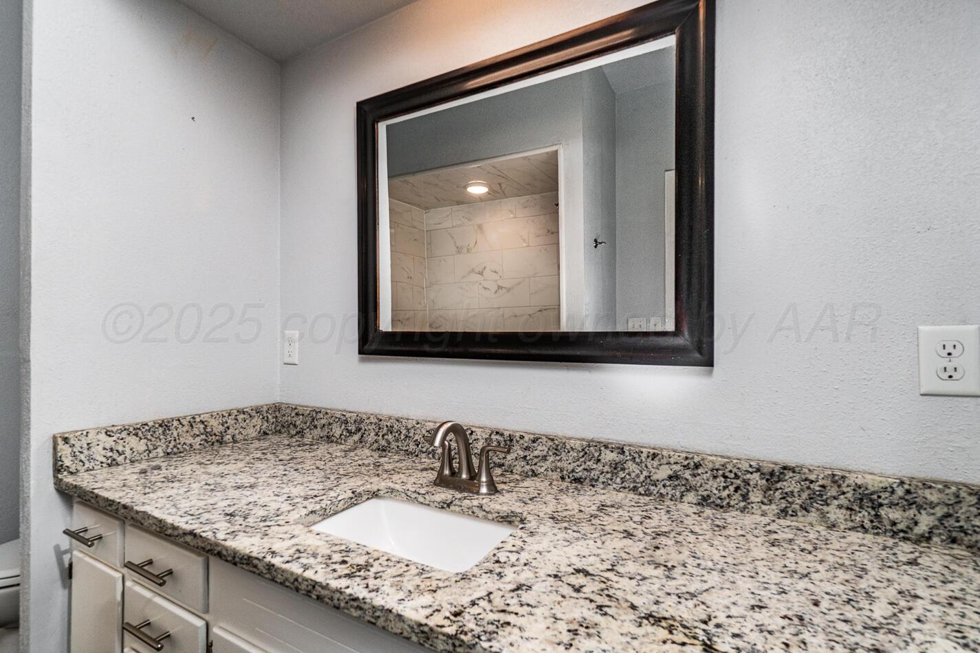 700 21st Street Canyon, TX 79015 - Photo 23 of 30 a bathroom with a granite countertop sink and a mirror