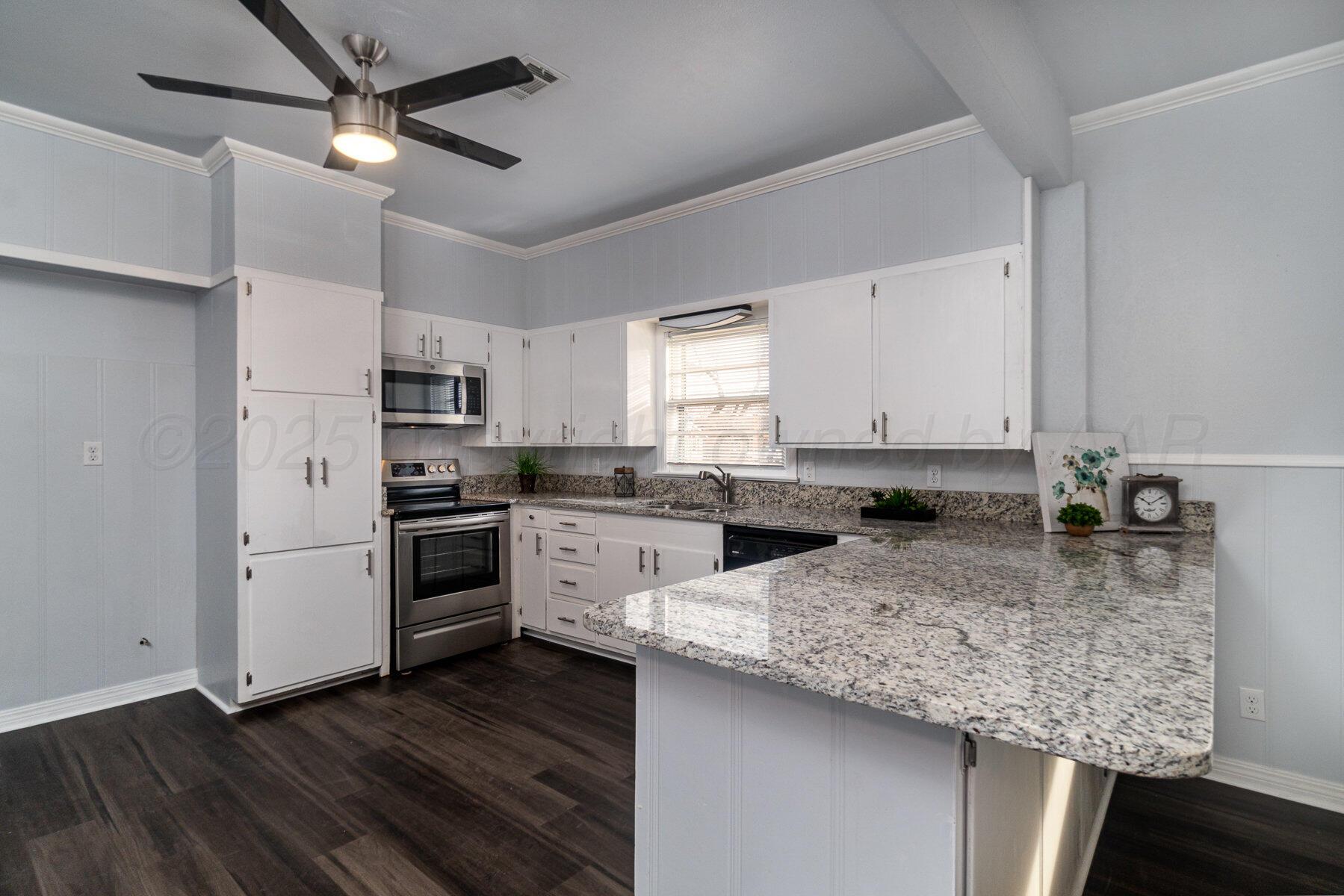 700 21st Street Canyon, TX 79015 - Photo 10 of 30 a kitchen with granite countertop a sink stainless steel appliances and white cabinets