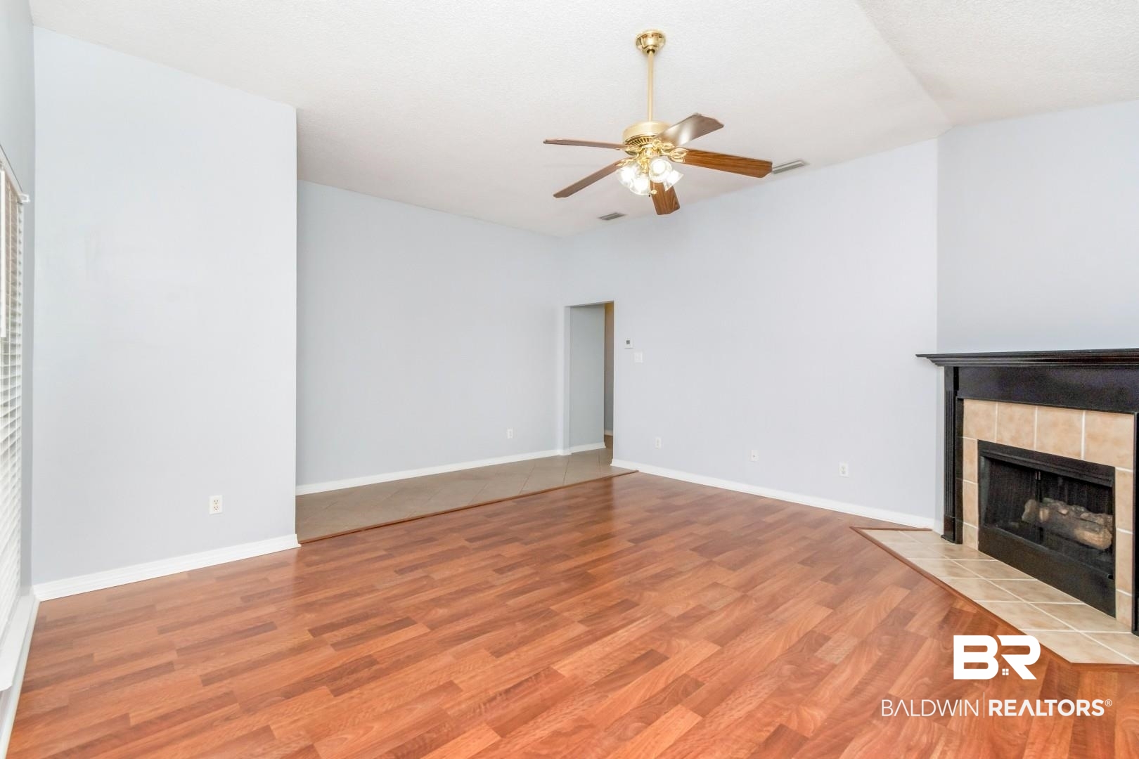 2136 Spring Grove Court Mobile, AL 36695 - Photo 5 of 38 Spacious living area featuring wood-finish flooring, a ceiling fan with integrated lighting, and a fireplace with a black mantel and tile surround