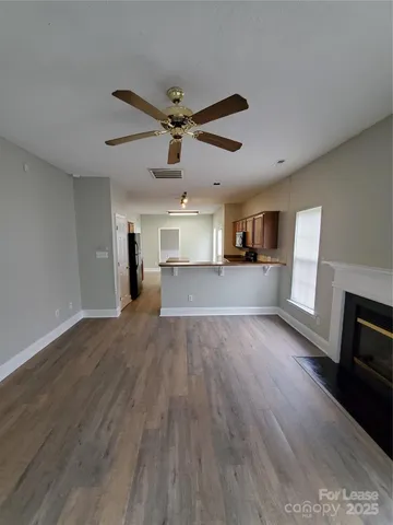 a view of a kitchen and an empty room with wooden floor and a kitchen