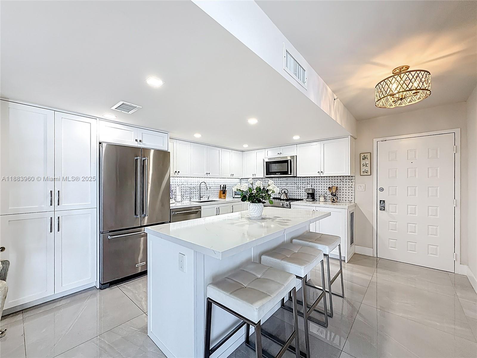 6061 Collins Avenue, Unit 20C Miami Beach, FL 33140 - Photo 7 of 29 a kitchen with refrigerator and chairs