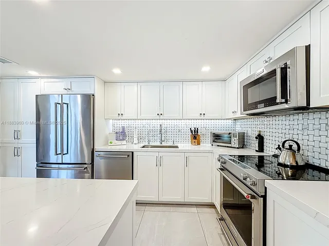 a kitchen with stainless steel appliances granite countertop a refrigerator sink stove microwave and cabinets