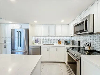 a kitchen with stainless steel appliances granite countertop a refrigerator sink stove microwave and cabinets