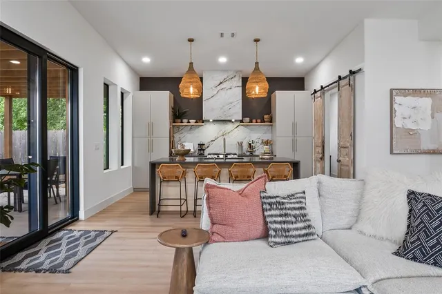 a living room with furniture a large window and stainless steel appliances