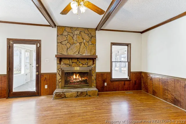 a view of an empty room with wooden floor and a fireplace
