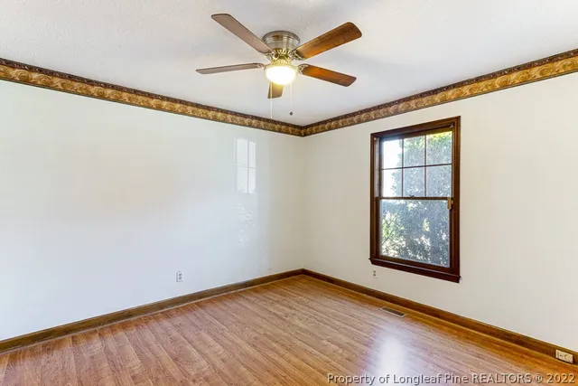 a view of an empty room with a window and wooden floor