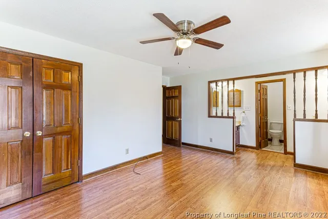 an empty room with wooden floor a ceiling fan and windows