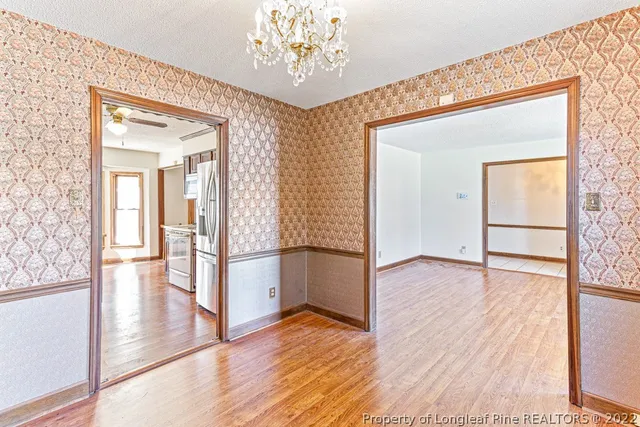 a view of a hallway with wooden floor and a living room