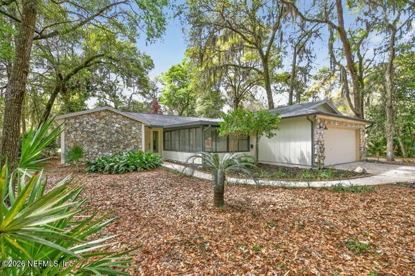 a view of a house with a yard and large tree