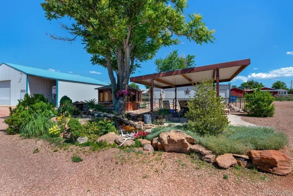 a backyard of a house with table and chairs under an umbrella