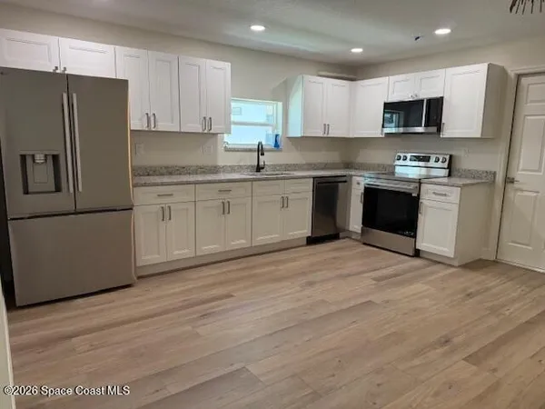 a kitchen with granite countertop a refrigerator stove top oven and sink