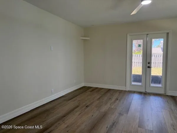 an empty room with wooden floor cabinet and windows