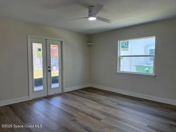 an empty room with wooden floor and ceiling fan