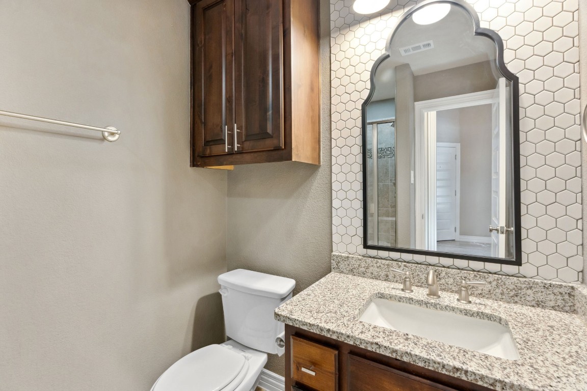 3929 Goodnight Trail Leander, TX 78641 - Photo 18 of 29 a bathroom with a granite countertop toilet sink and mirror
