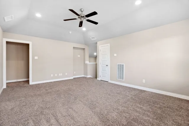 an empty room with windows and ceiling fan