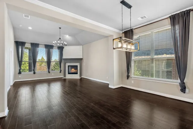 an empty room with wooden floor a fireplace and a window