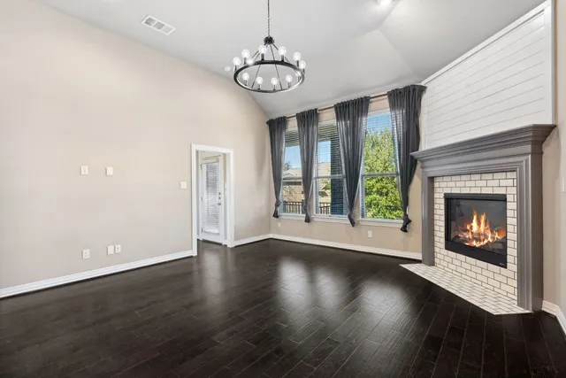 a view of an empty room with wooden floor fireplace and a window