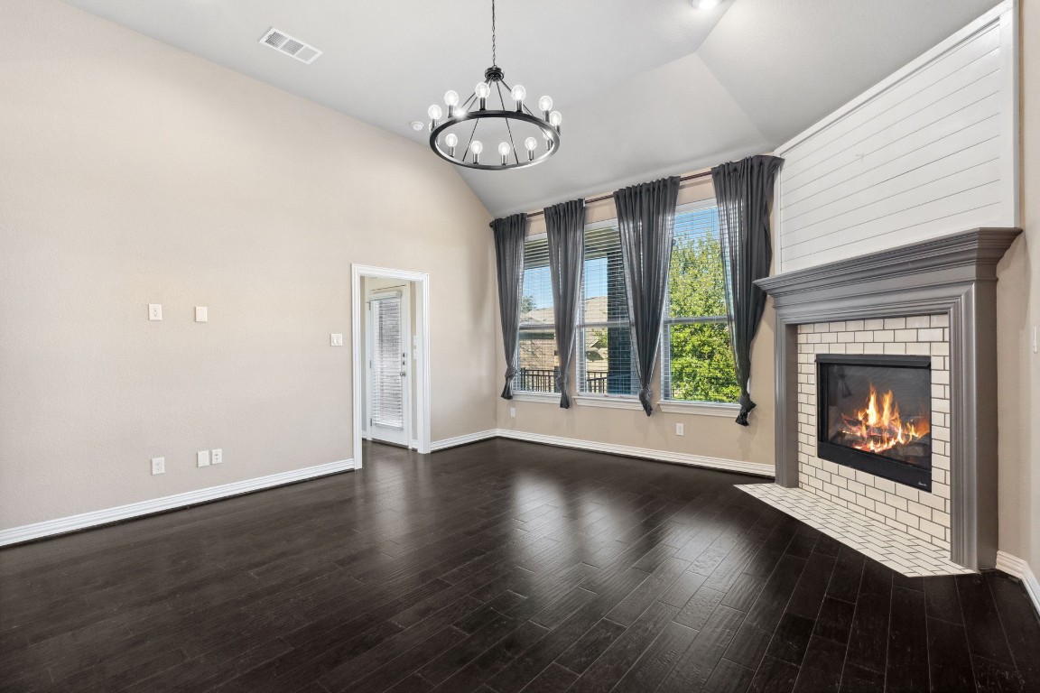 3929 Goodnight Trail Leander, TX 78641 - Photo 5 of 29 an empty room with wooden floor a fireplace and a window