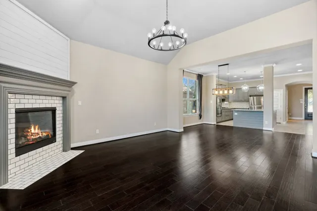 a view of a hallway with wooden floor and a kitchen
