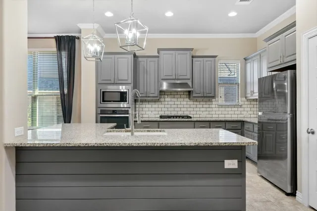 a kitchen with granite countertop a refrigerator sink and cabinets