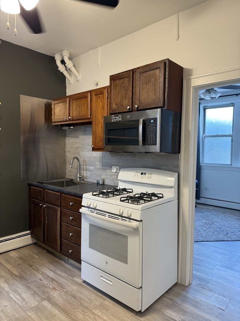 6000 West Seminole Street, Unit GDN Chicago, IL 60646 - Photo 6 of 7 a kitchen with stainless steel appliances wooden cabinets and a stove top oven