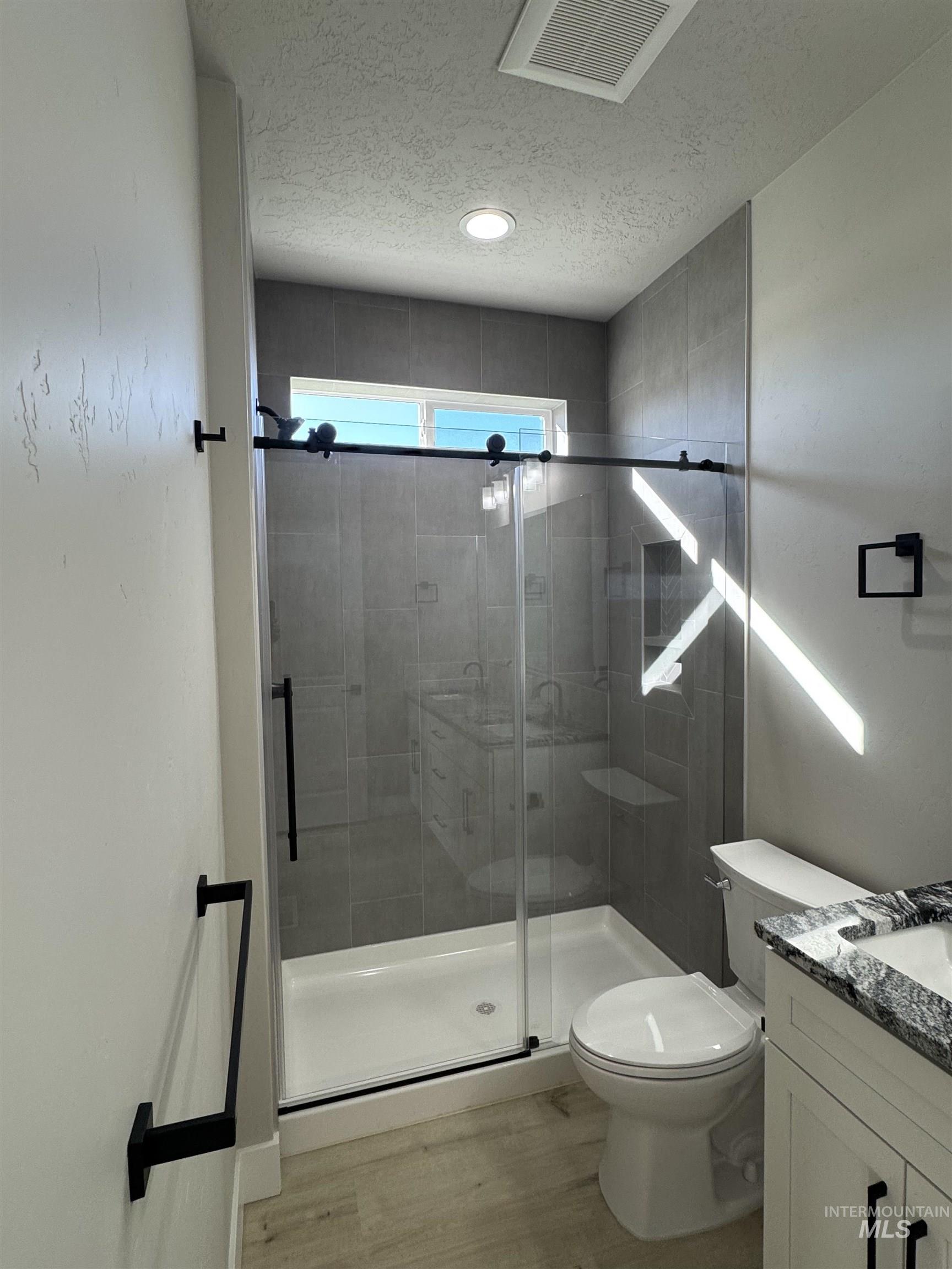 23735 Legends Lane Caldwell, ID 83607 - Photo 23 of 34 Full bathroom featuring vanity, a textured ceiling, a shower stall, and light wood finished floors