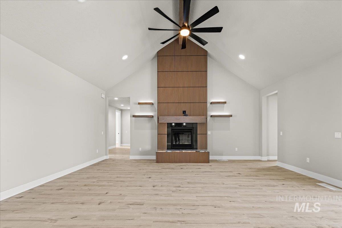 23735 Legends Lane Caldwell, ID 83607 - Photo 10 of 34 Unfurnished living room featuring a fireplace, light wood-style floors, high vaulted ceiling, a ceiling fan, and recessed lighting
