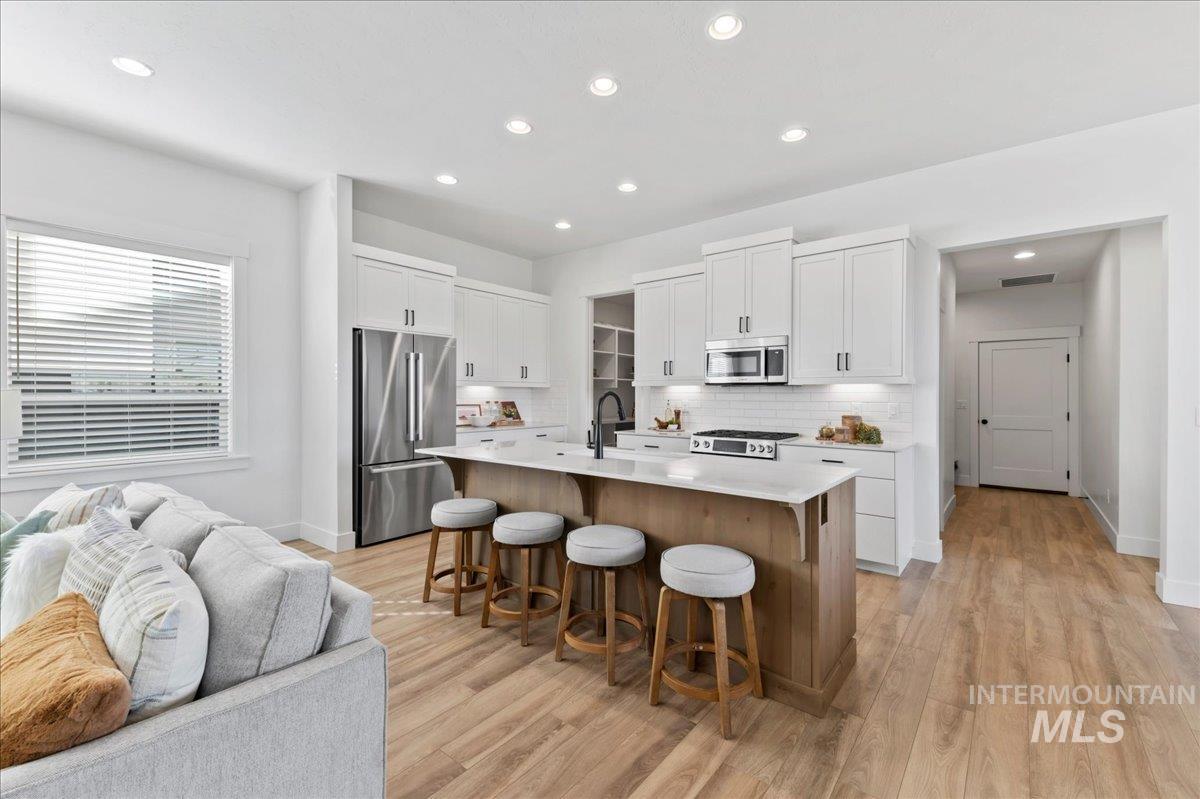 6370 North Barholm Lane Eagle, ID 83616 - Photo 15 of 33 Kitchen with decorative backsplash, white cabinets, stainless steel appliances, an island with sink, and recessed lighting