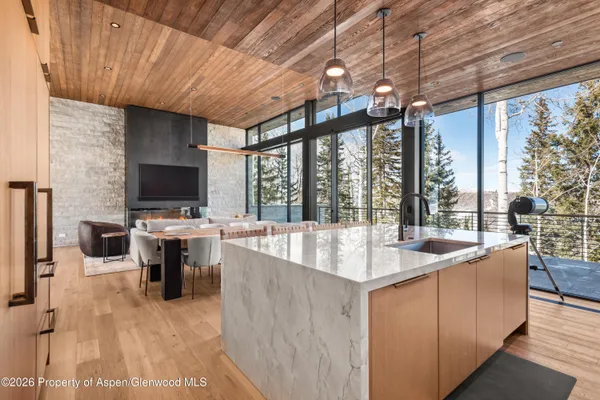 a living room with couches a flat screen tv and kitchen view